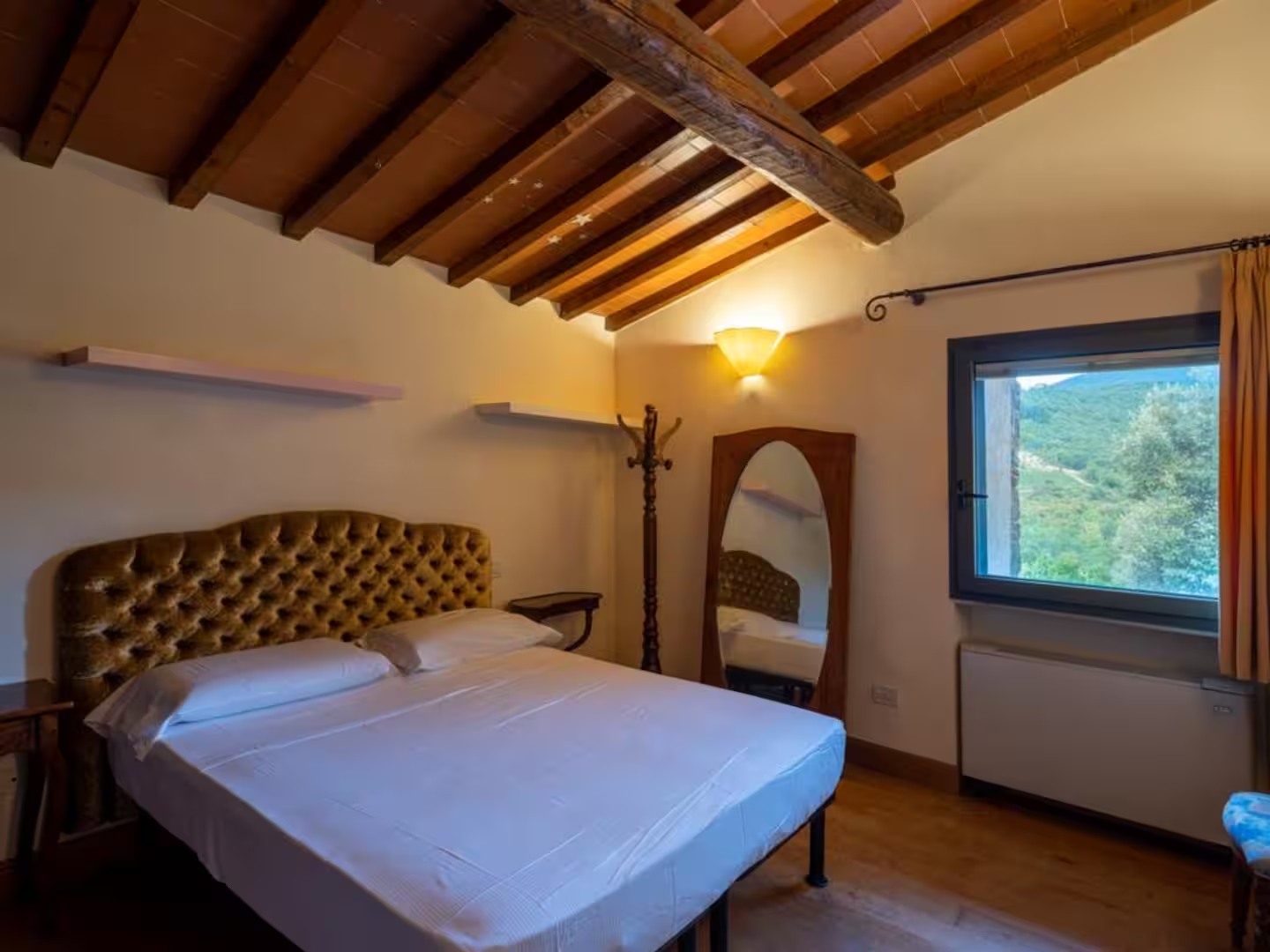 Warmly furnished villa bedroom with a window overlooking greenery